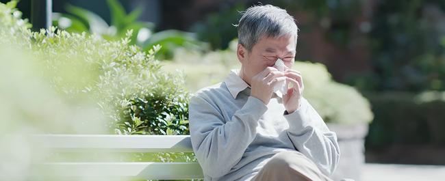 A man sneezing due to seasonal allergies.