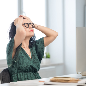 Mature woman suffering headache in the office.