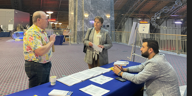Drs. Garth Ehrlich, Drexel Medicine Diagnostics (DMD) section director (standing, left) and Donald C. Hall, Jr., DMD operations director (seated), speaking with a potential client at Drexel University's 2022 Discovery Day, Philadelphia Convention Center.